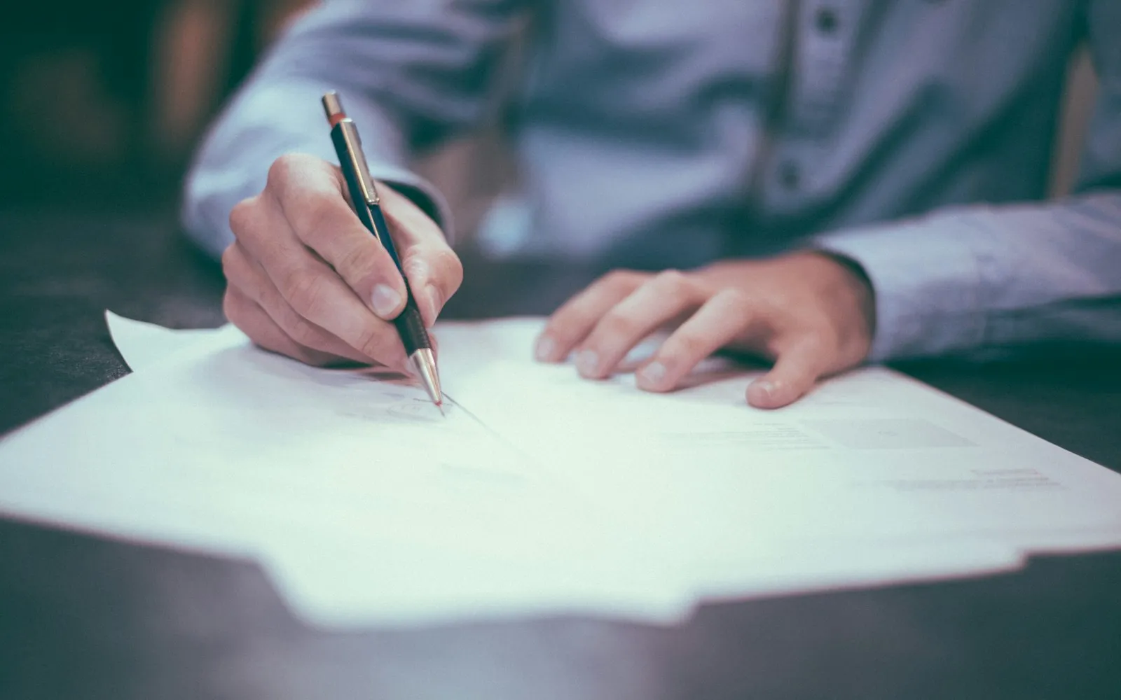 Close-up of a person signing an official document at a desk